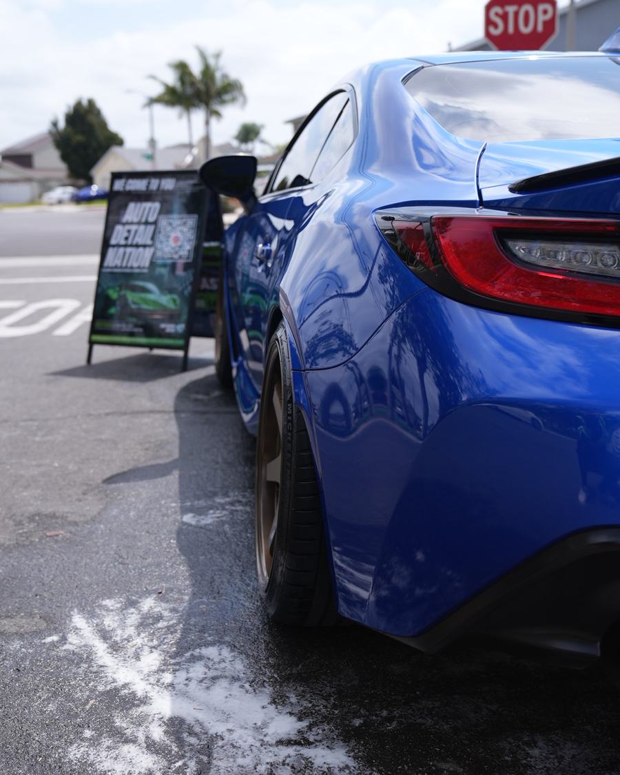 Blue sports car after an exterior wash, with the We Come To You sign